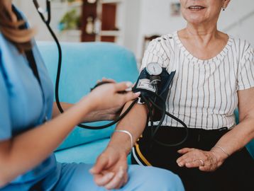 A nurse measures an elderly woman's blood pressure using a sphygmomanometer.