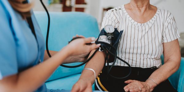 A carer measures an elderly woman's blood pressure using a sphygmomanometer.