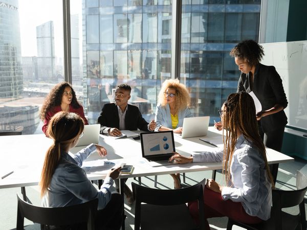 A diverse group discussing business data in a modern office with city views.