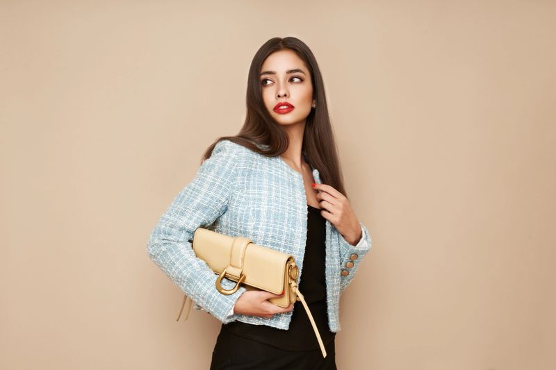 Young brunette woman in blue jacket. Model posing in a business suit. Girl  with beige handbag. Fashion photo