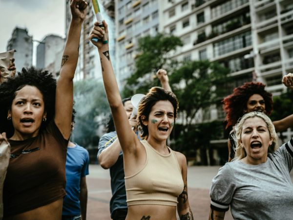 A diverse group of people raising fists in a public protest outdoors.