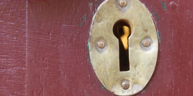 Close-up of old brass keyhole on red door.