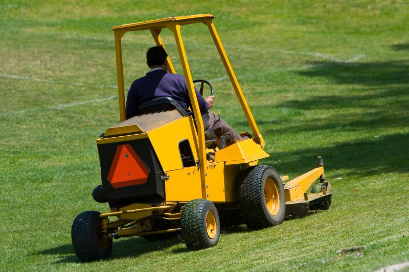 A man cutting grass on a lawn mower.