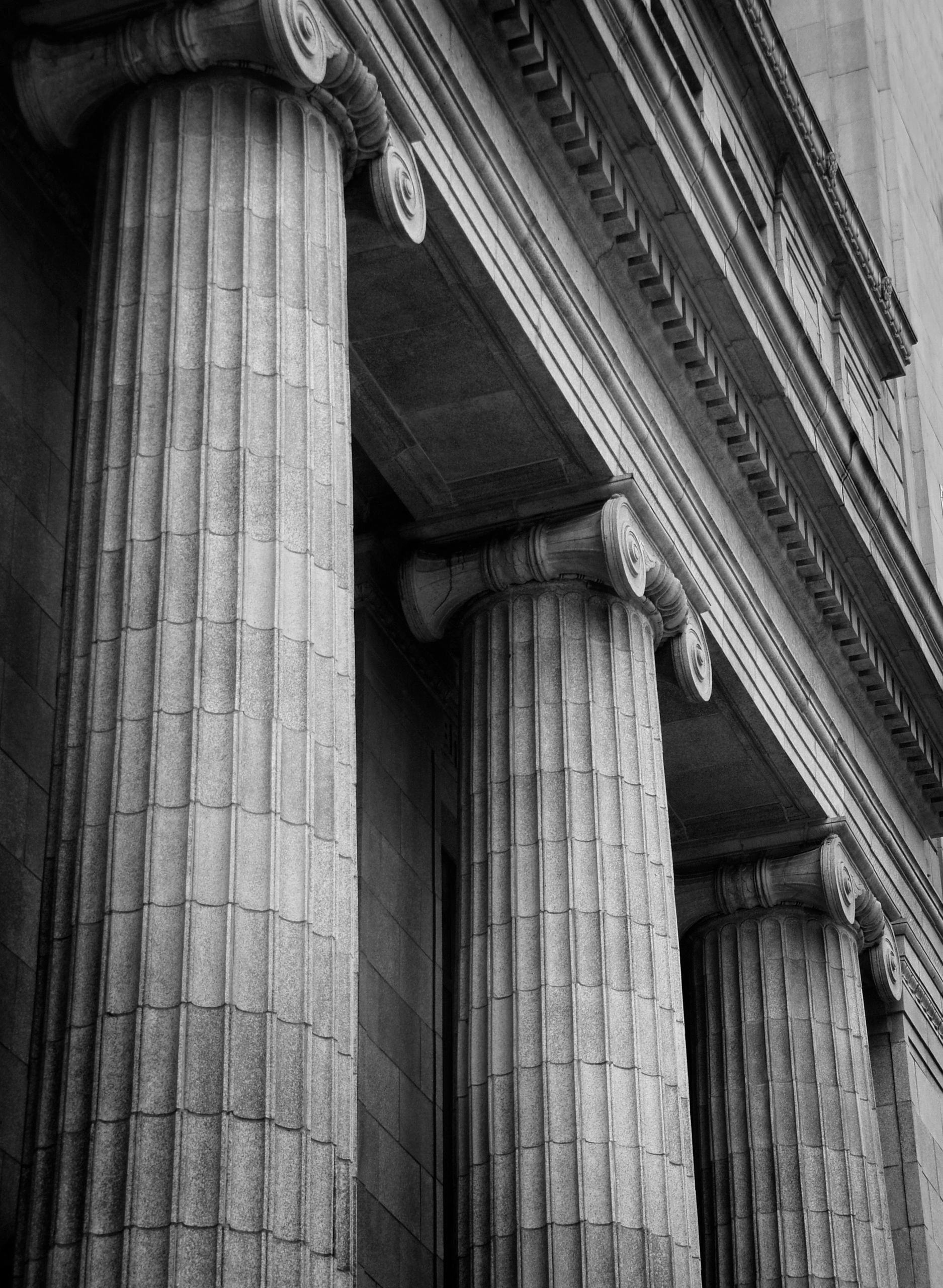 Close-up of classical stone columns with intricate capitals on a historic building.