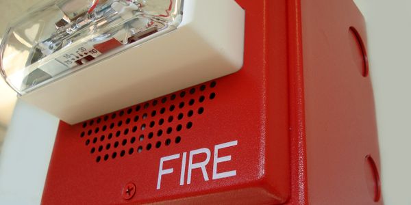 Close-up of a red fire alarm with a white strobe light.