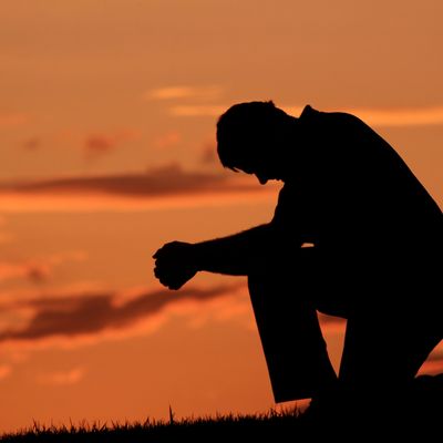 Silhouette of a person kneeling at sunset.