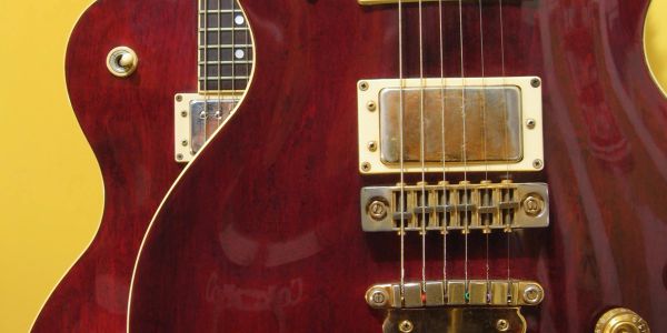 Close-up of a red electric guitar's body and strings.