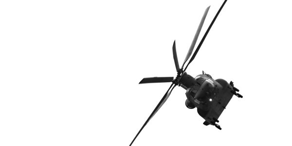 Black and white image of a military helicopter in flight against a white sky.