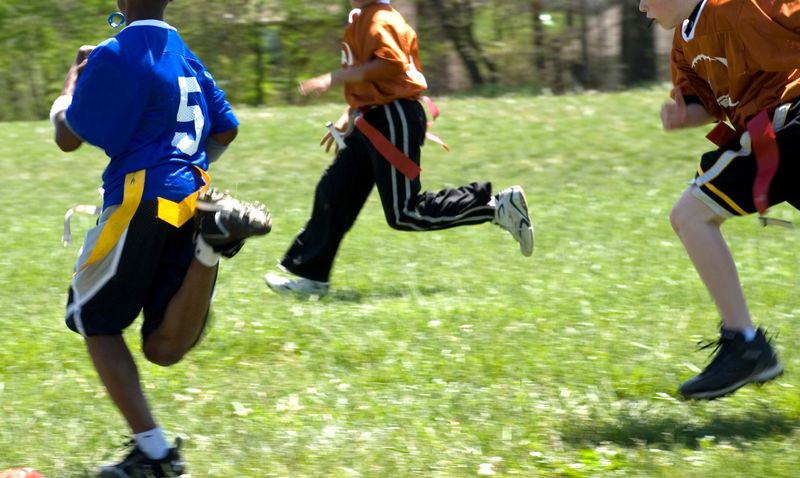 Boys playing American flag football in summer.