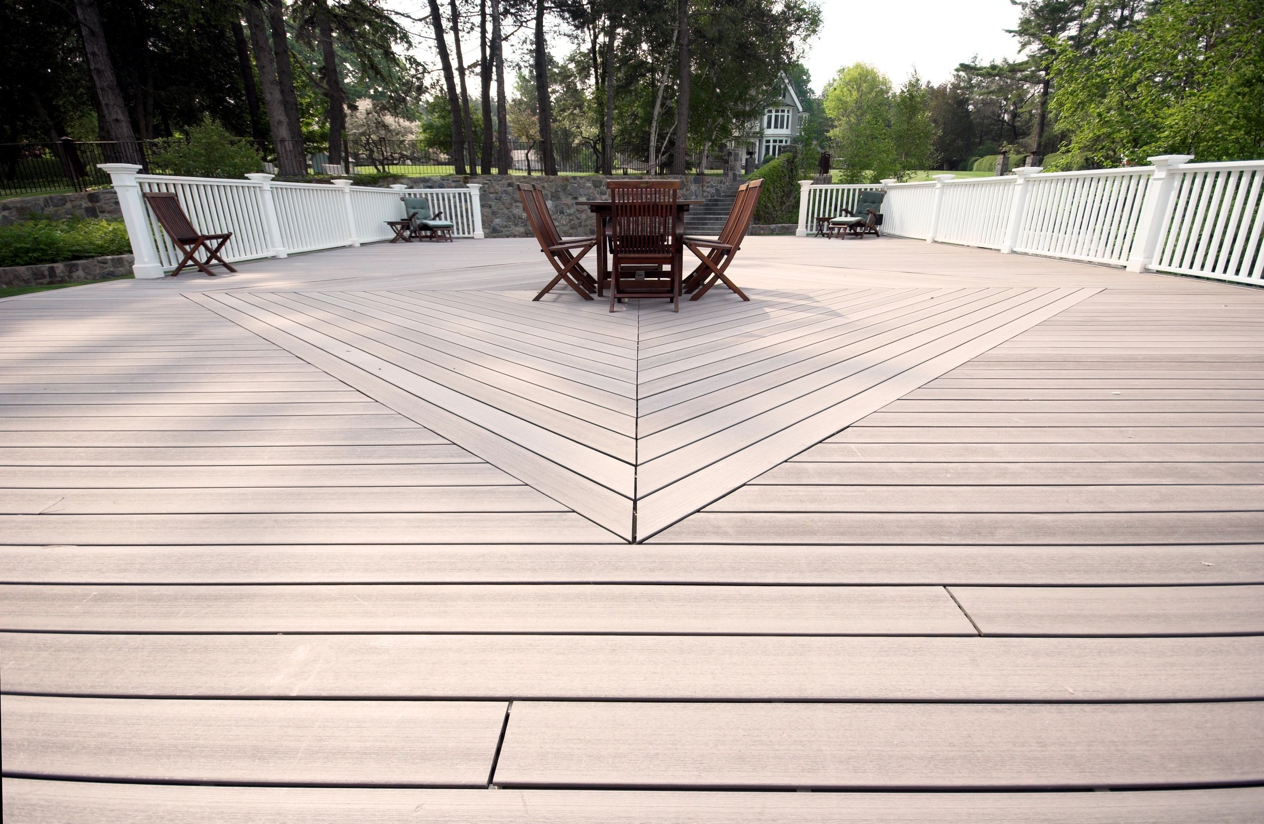 Spacious wooden deck with outdoor furniture and white railing.
