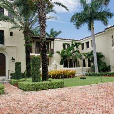 Elegant Mediterranean-style house with lush palm trees and manicured garden.