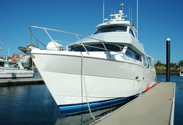 A large white yacht docked at a marina on a clear sunny day.