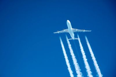 Airplane flying with contrails against a clear blue sky.