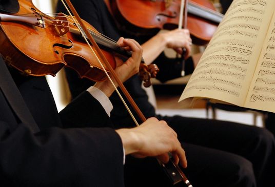 Musicians playing violins with sheet music in view.