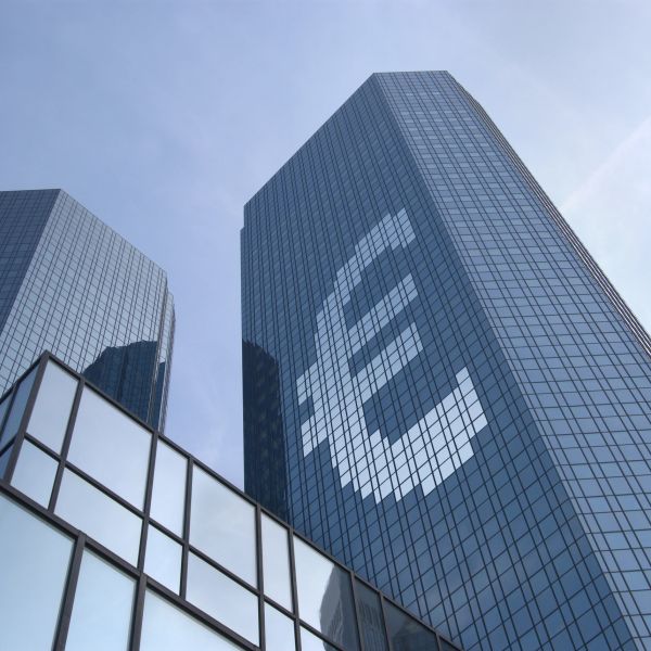 Tall glass skyscraper with a large Euro symbol reflected on its facade.