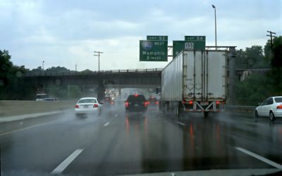 Rainy highway scene with vehicles and road signs.
