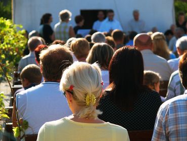 Audience attentively watching an outdoor event on a sunny day.