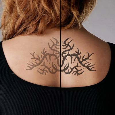Back tattoo design on a person's upper back with tribal style elements.