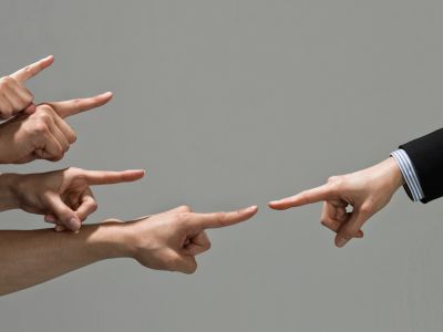 Several hands pointing at a single hand from the right.
