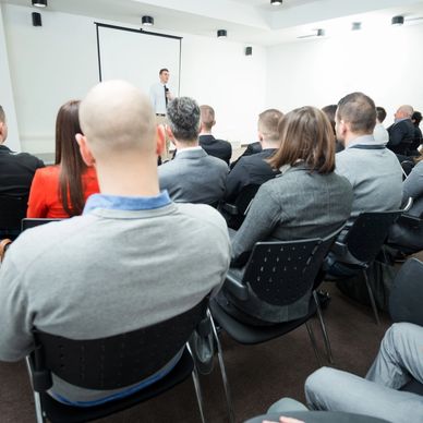 A man giving a presentation to a seated audience in a conference room.