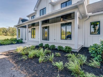 A modern farmhouse with a stylish black and white exterior, a welcoming porch, and freshly landscaped front yard.