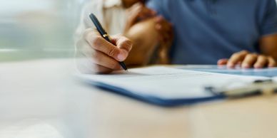 Person signing a document with a pen.