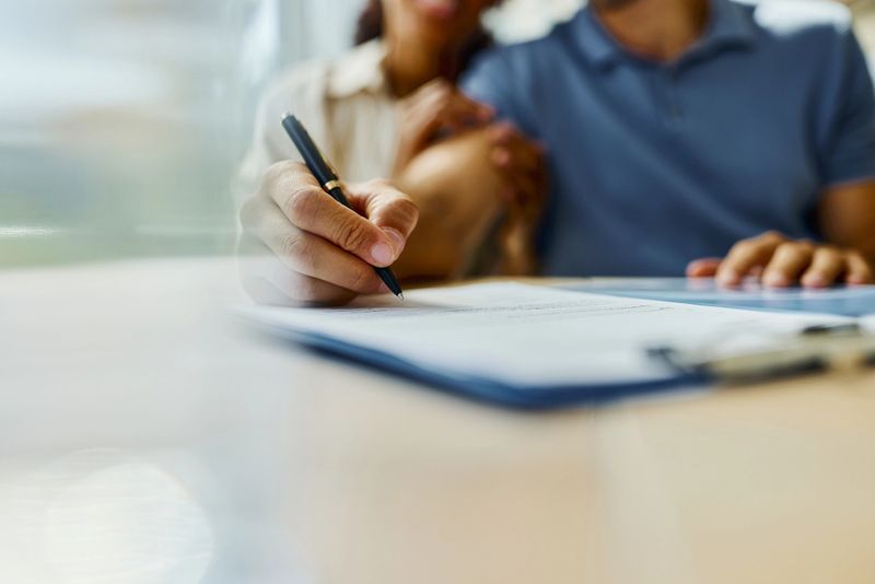 Close up of unrecognizable insurance agent showing his customer where to sign the contract. Copy space.