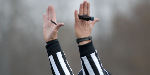 Referee signals with both hands raised during a game.