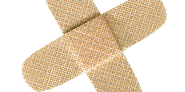 Two adhesive bandages crossed over each other on a white background.