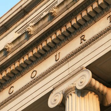 Close-up of courthouse facade with classical columns and lion head sculptures.
