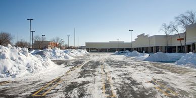 Snow-covered parking lot with piled snow mounds.
