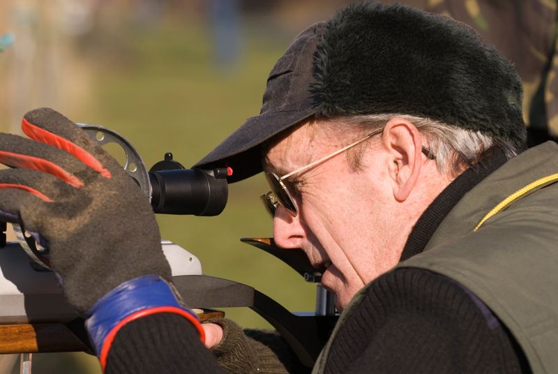 A competitor in a field target shooting competition focusing a telescopic sight.
