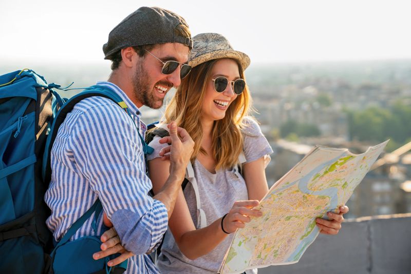 Happy smiling couple on vacation sightseeing city with map. People travel fun love concept.