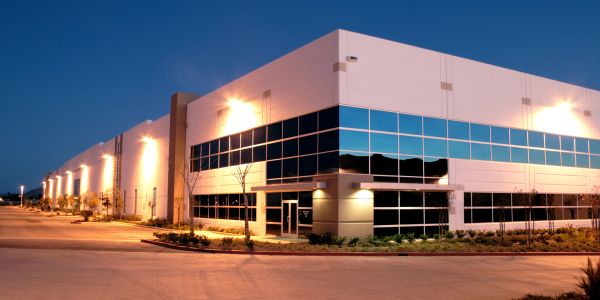 Modern industrial building at dusk with illuminated exterior lights.