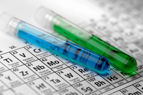 Test tubes with blue and green liquids on a periodic table.