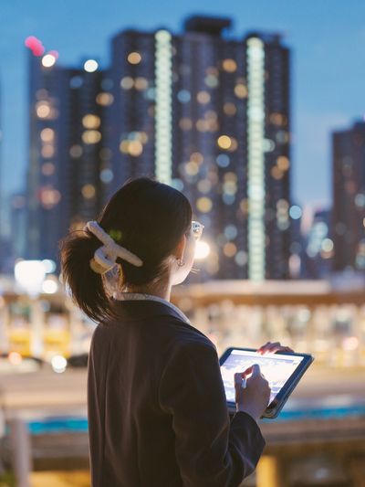 Person using tablet at night in city.