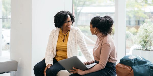 Two women talking and smiling in a bright room.