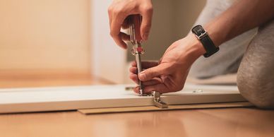 A person screwing a screw into a shelf.