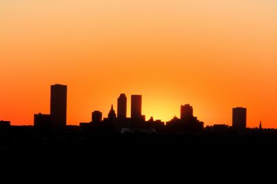 City skyline silhouetted against a vibrant orange sunset.