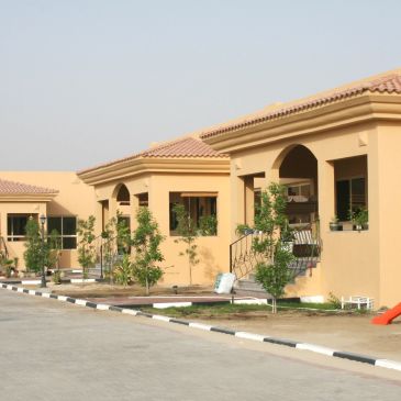 Row of beige houses with tiled roofs and small front gardens.
