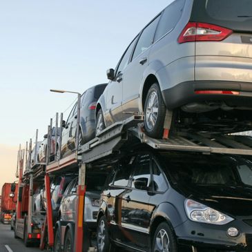 A car transporter carrying multiple vehicles on a highway.