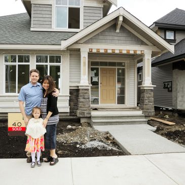 Happy family standing in front of their newly sold house under construction.