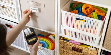Person labeling storage drawers in a neatly organized room.