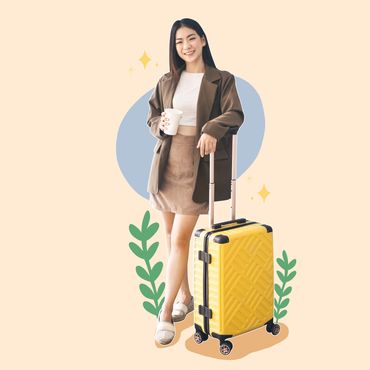 A smiling woman standing beside a yellow rolling suitcase. She is wearing casual travel clothes and 