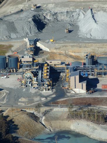 Industrial mining site with machinery and a large excavation area.