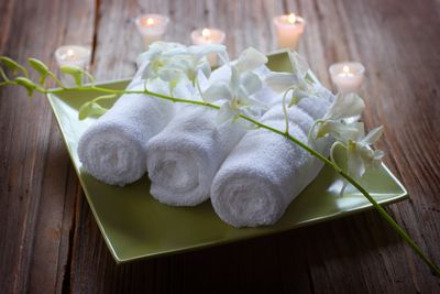 Rustic spa setup with salt bowls, herbs, and flowers on a wooden table.