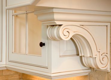 Close-up of ornate white cabinet corner with decorative corbel.
