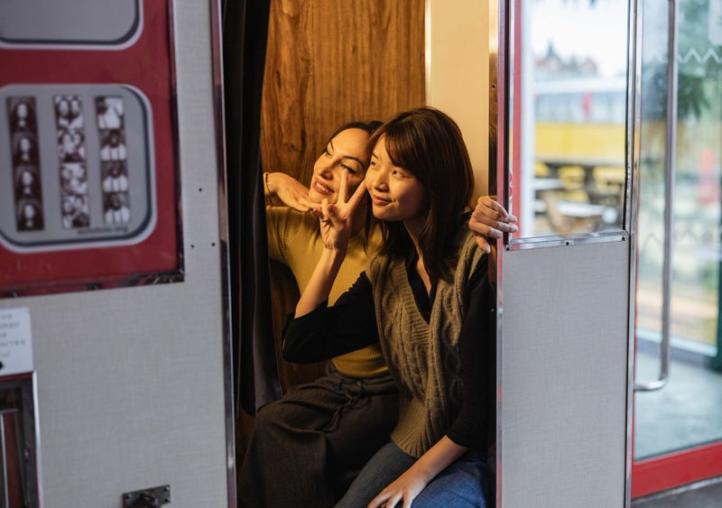 two multiracial lesbian women take photos in a photo booth