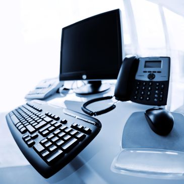 Modern office desk setup with computer, keyboard, mouse, and phone.