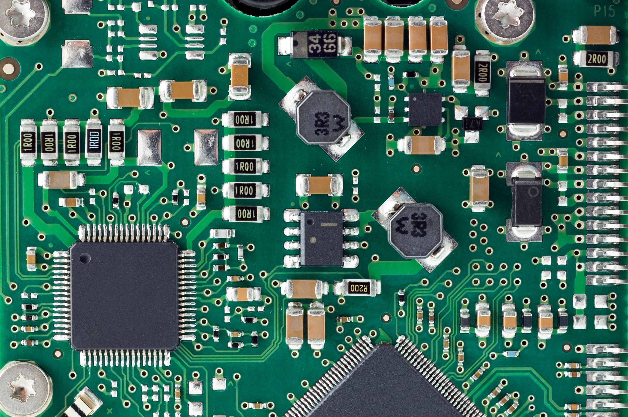 Close-up of a green circuit board with microchips and components.